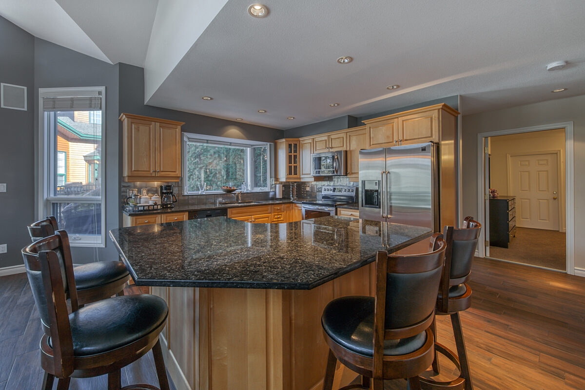 Kitchen with barstools, modern appliances, and cooking space.