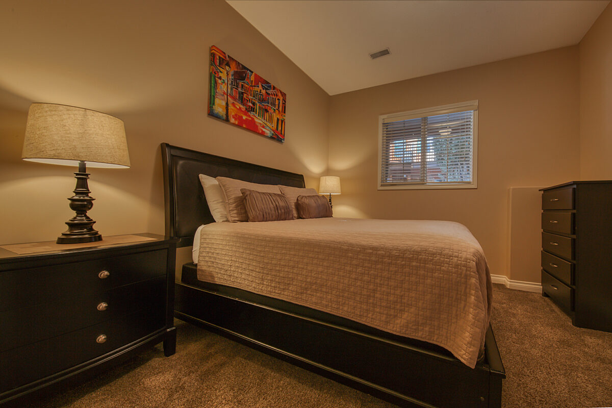 Queen bedroom with grey bedding and window to the right.