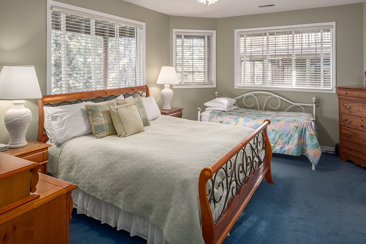 King bedroom with twin bed. Bedside tables and lamps on either side of the bed, window to the right.