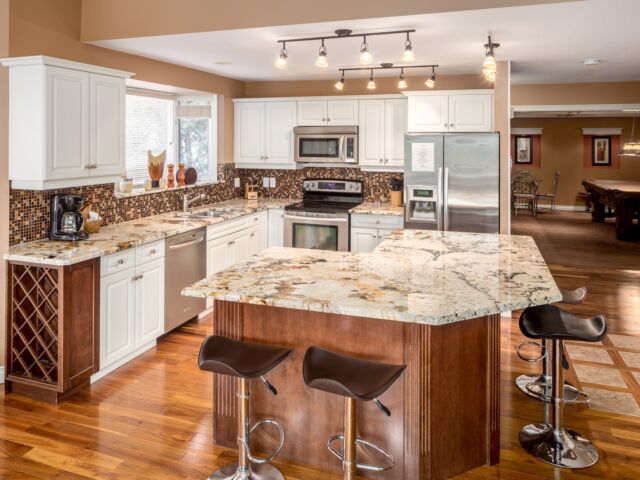 Spacious kitchen with island, barstools, appliances, and dining space to the rear.
