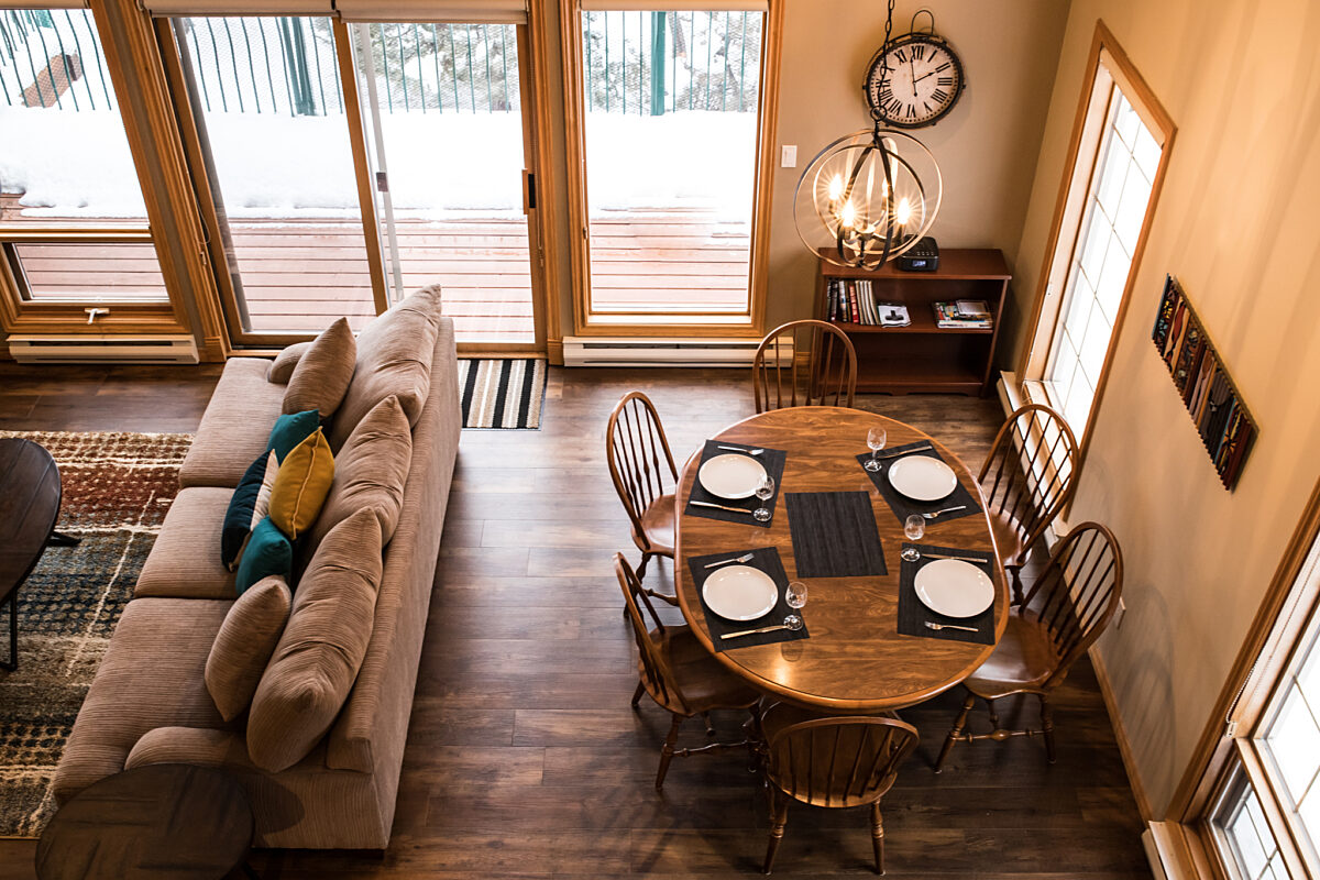 Living and dining areas as viewed from a loft above. Table and chairs, couch, and coffee table included.
