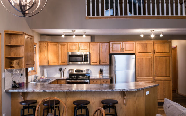 Living and dining areas as viewed from a loft above. Table and chairs, couch, and coffee table included.