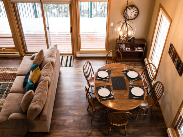 Living and dining areas as viewed from a loft above. Table and chairs, couch, and coffee table included.