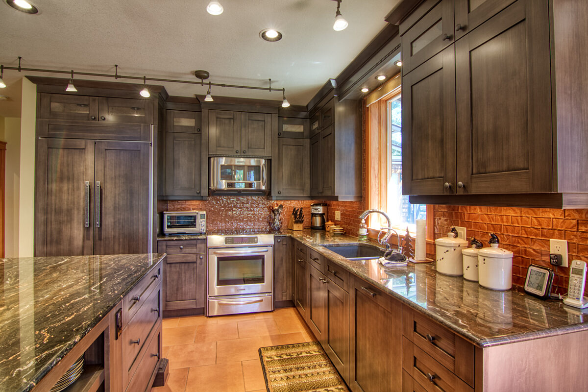 Large kitchen area with wide stretches of countertop, a stainless steel oven and appliances.