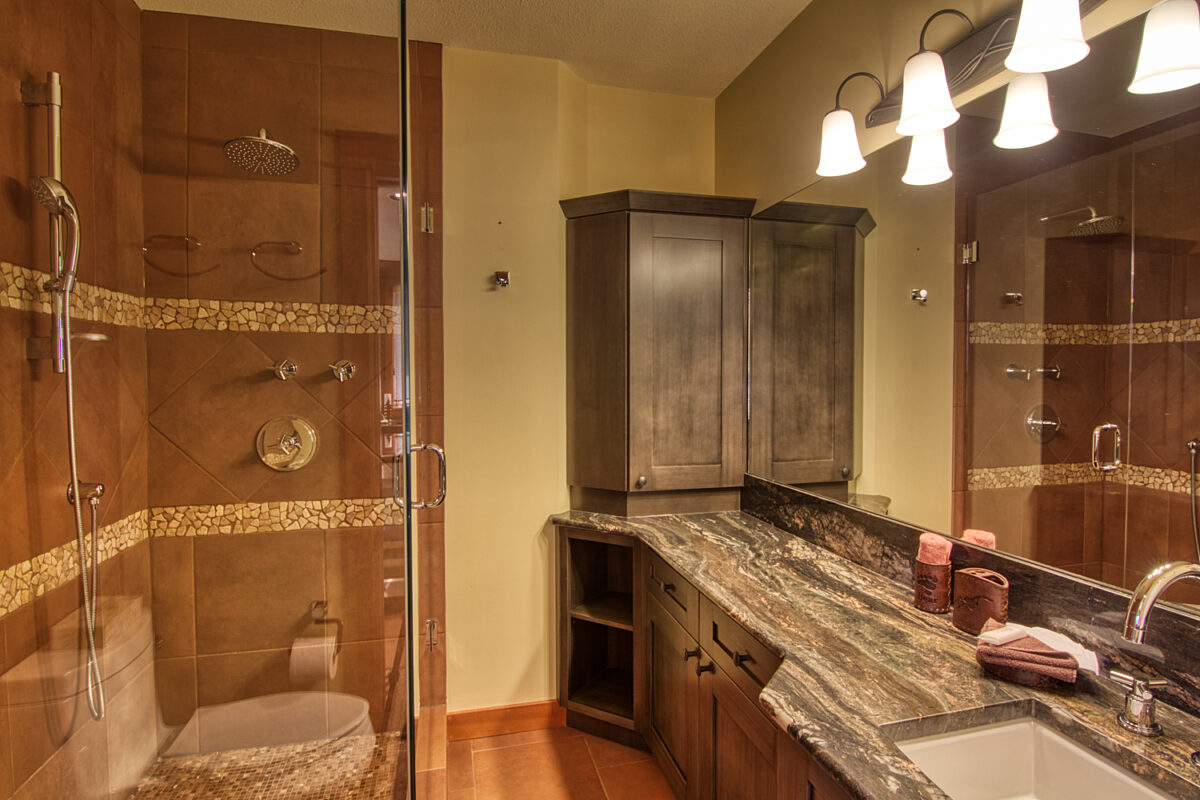 Bathroom with tiled shower, large mirror and lighted vanity.