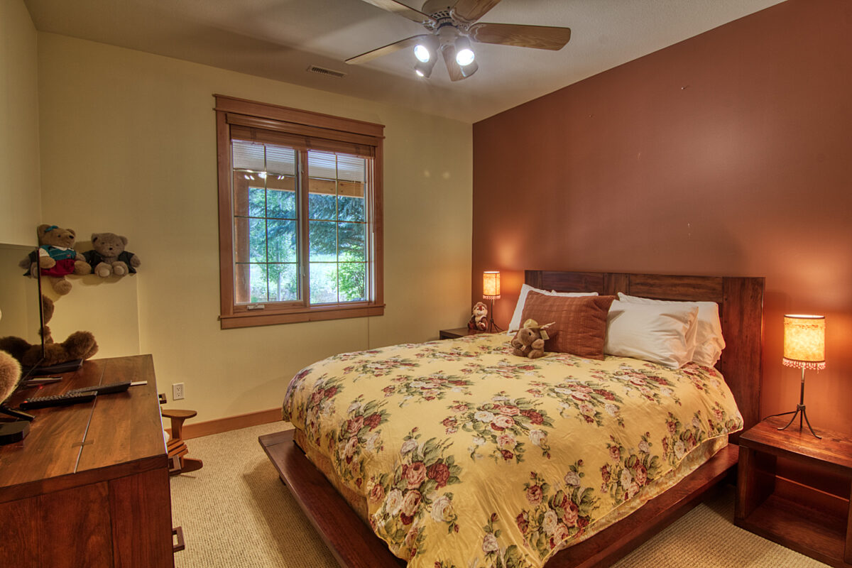 Bedroom with king size bed, rose patterned bedding, salmon coloured walls. Teddy bears for decoration.