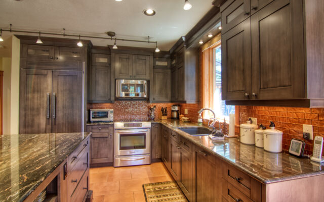 Wood paneled porch hot tub on a deck with its lid off. The water in the hot tub is clear. Porch overlooks treed area.