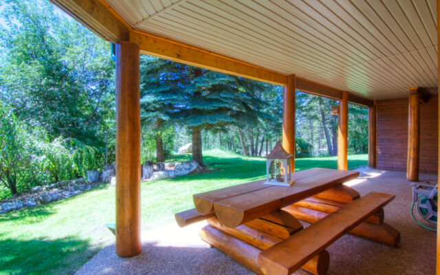 Wood paneled porch hot tub on a deck with its lid off. The water in the hot tub is clear. Porch overlooks treed area.