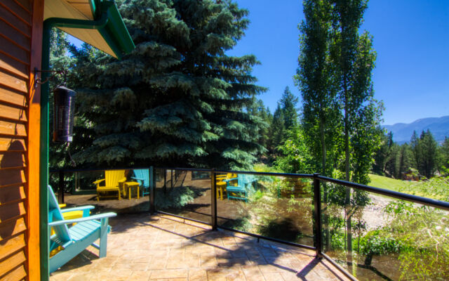 Wood paneled porch hot tub on a deck with its lid off. The water in the hot tub is clear. Porch overlooks treed area.