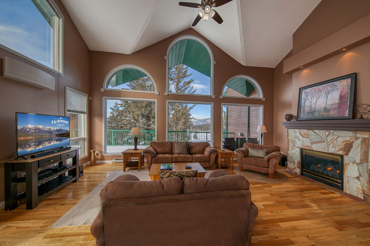 Living room with fireplace, couch, and large windows.