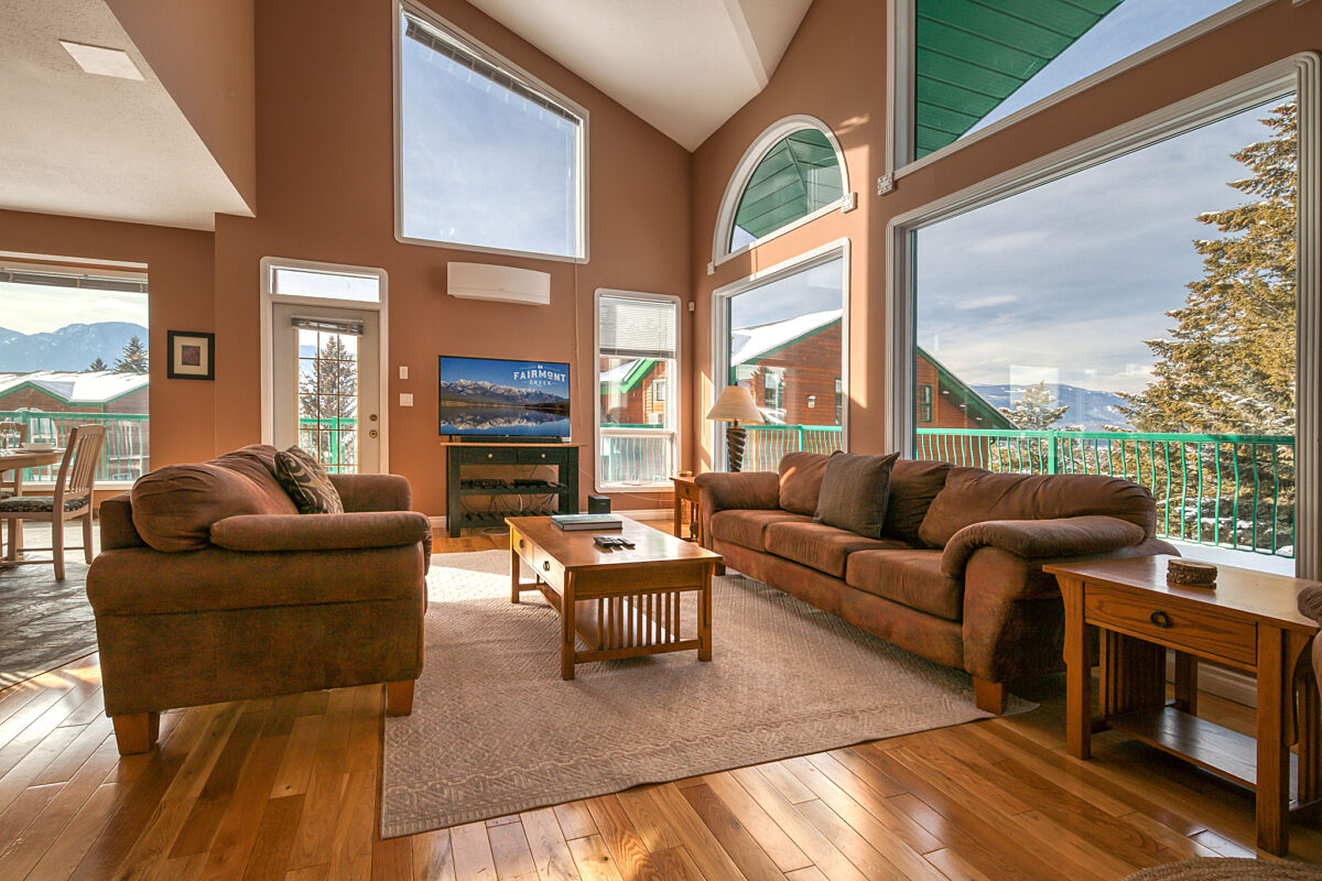 Living room with large picture windows. Two couches and a coffee table in the seating area.
