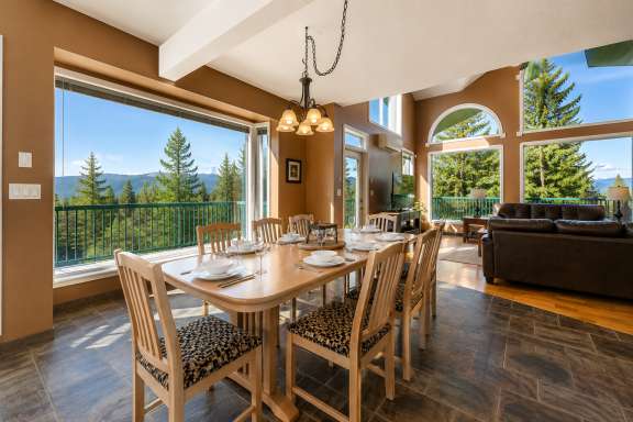 Dining area at Marble Canyon 102 - Phase 1 with seating for 8, floor-to-ceiling windows, open-concept living space and stunning golf course and mountain views.