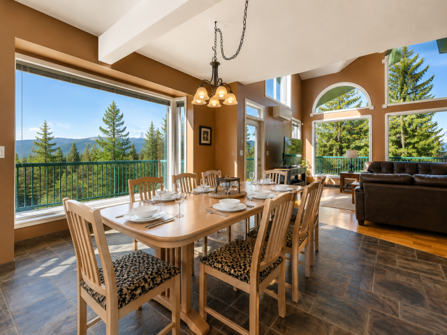 Dining area at Marble Canyon 102 - Phase 1 with seating for 8, floor-to-ceiling windows, open-concept living space and stunning golf course and mountain views.