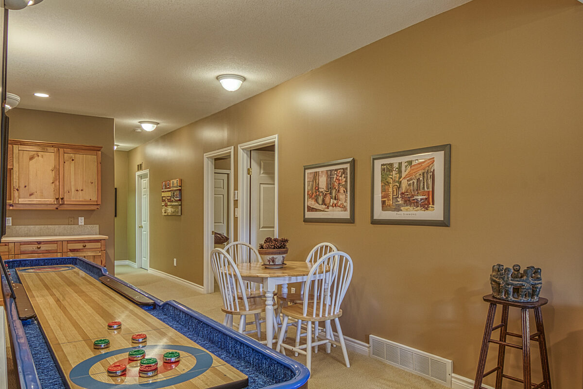 Shuffleboard with a nearby table and chairs, wet bar, and hallway.