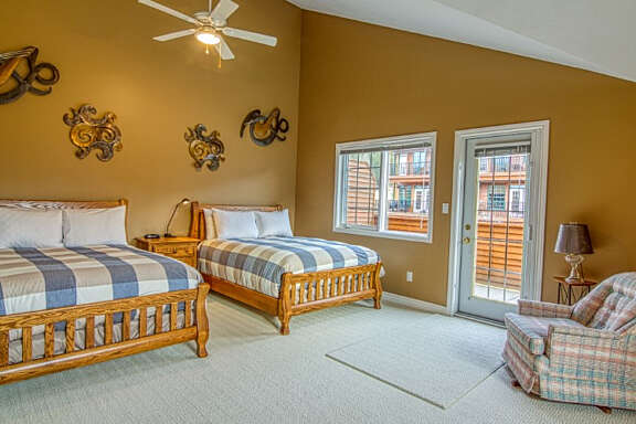 Bedroom with two queen size beds, plaid bedding, and brown walls.