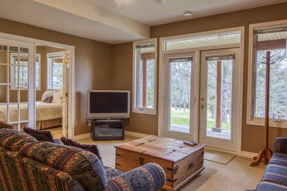 A downstairs living room featuring a couch, walk out patio, and nearby bedroom with glass french doors.