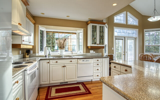 Dining room and living room as viewed from the loft above. Light wood dining table and chairs, blue couch and chair, rug, coffee table, and fireplace.
