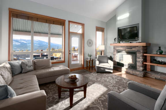 Living room with couches, fireplace, television, and large windows to the left.