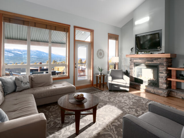 Living room with couches, fireplace, television, and large windows to the left.