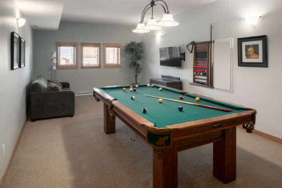 Recreation room with pool table, chairs, and windows to the rear.
