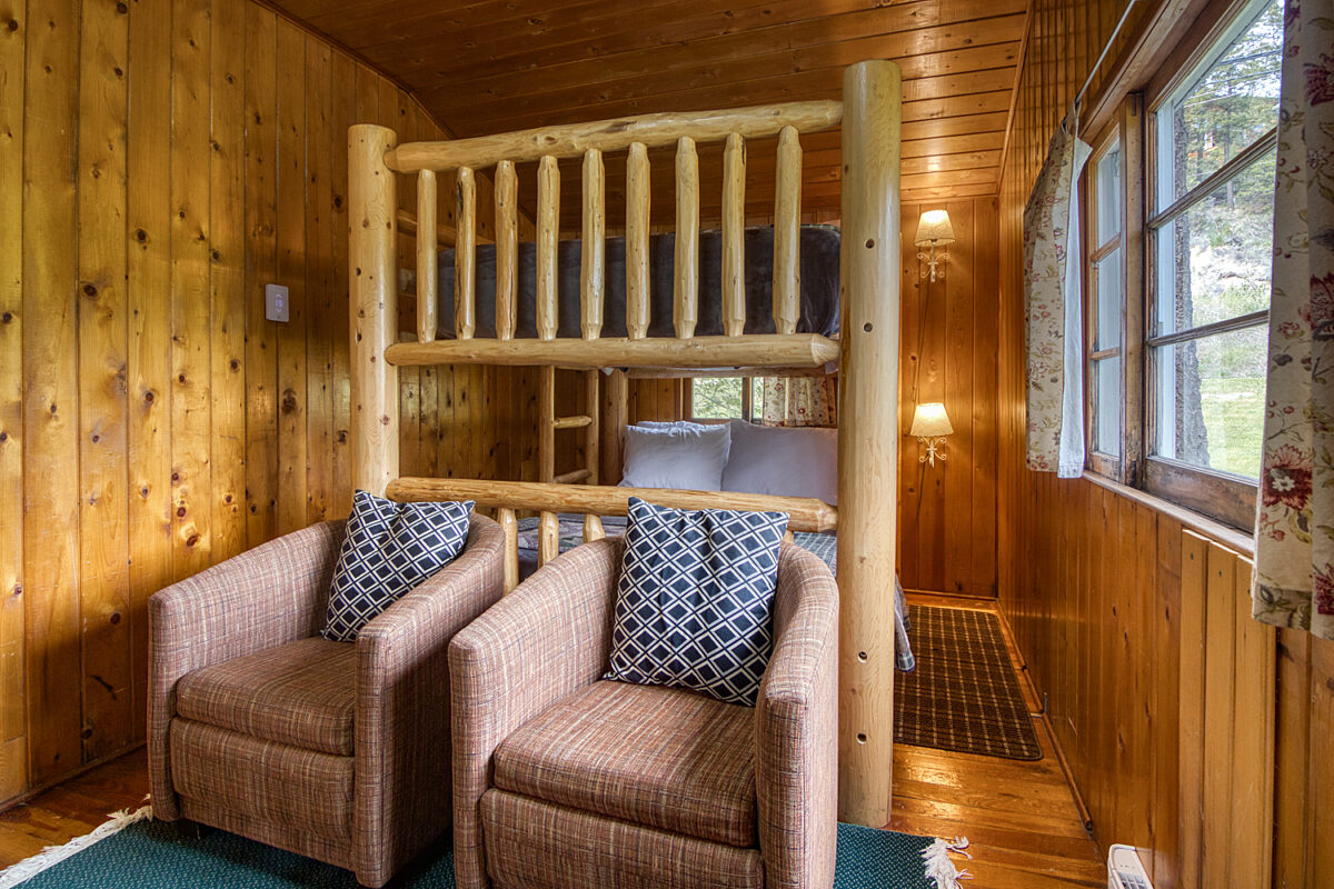 Double bunk bed bedroom with two chairs and window to the right.