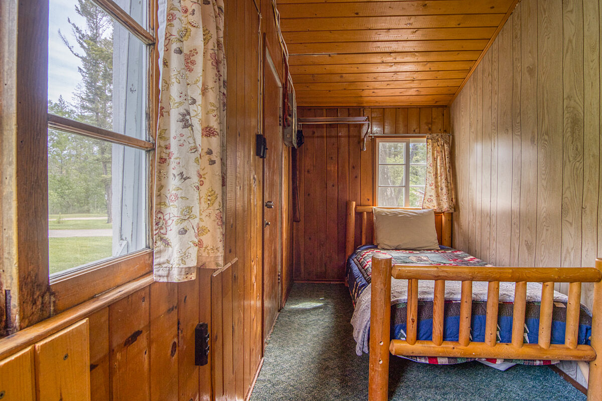 Single bed in wood panelled bedroom.