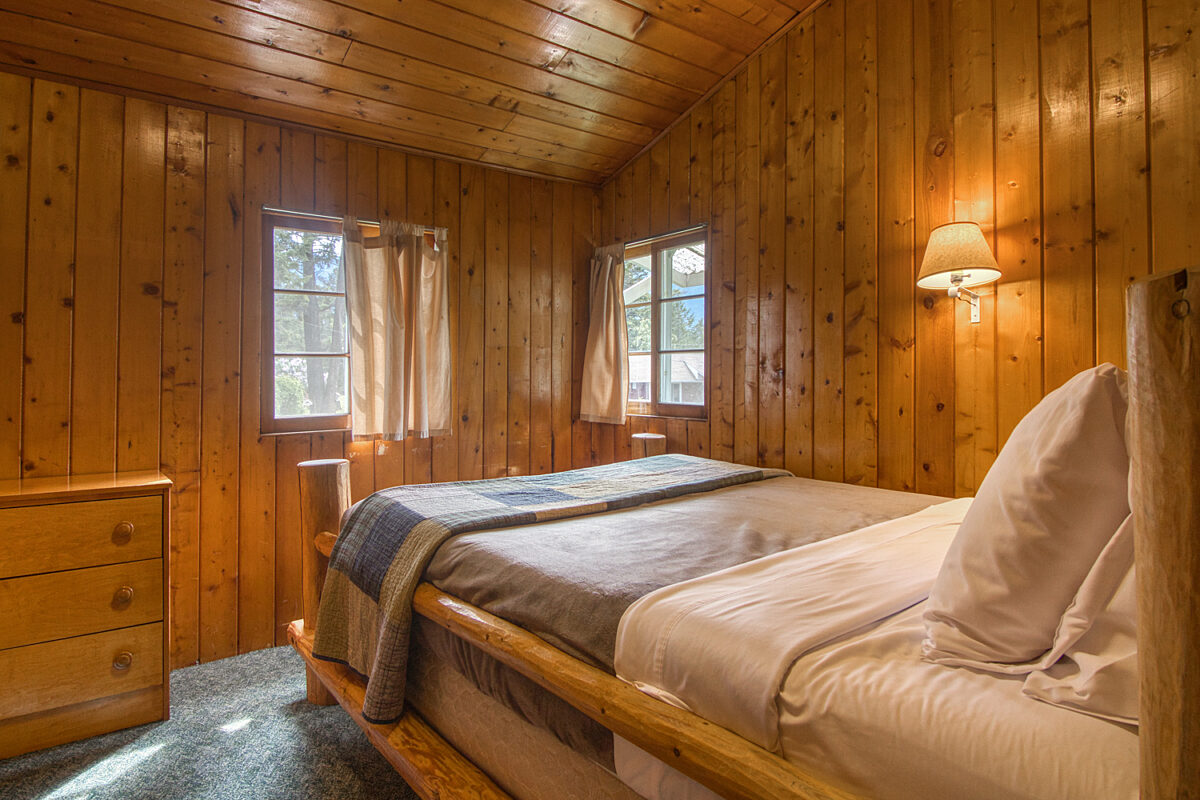 Queen bedroom with wood panelling and lamp over bed.