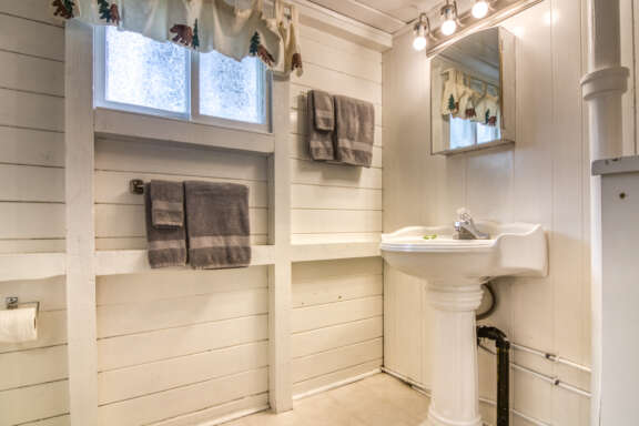 Bathroom area with white panelled walls and a white sink.