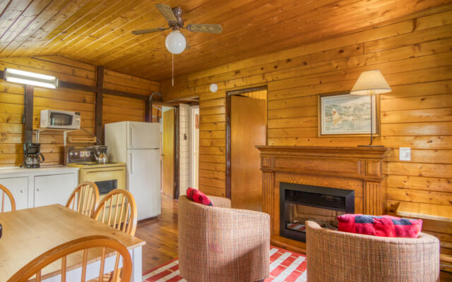 Small red cabin with two red outdoor lounge chairs outside. Trees and greenery surrounding.