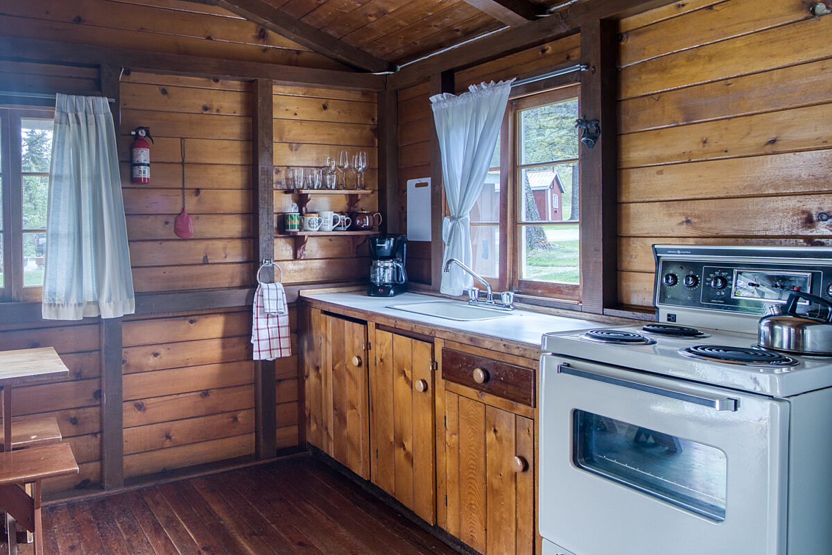 Kitchen space in wood panelled cabin with white appliances.
