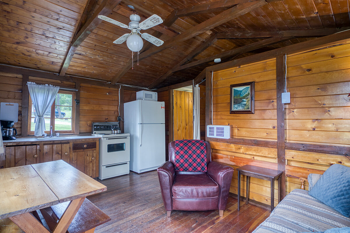 Kitchen area in wood panelled cabin. White appliances and counterspace.