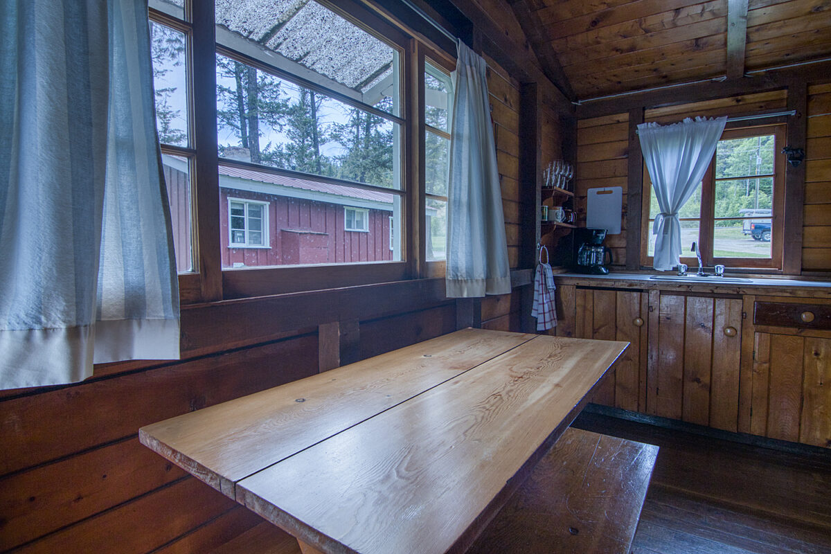 Dining area in wood panelled cabin. Picnic-style rustic table.