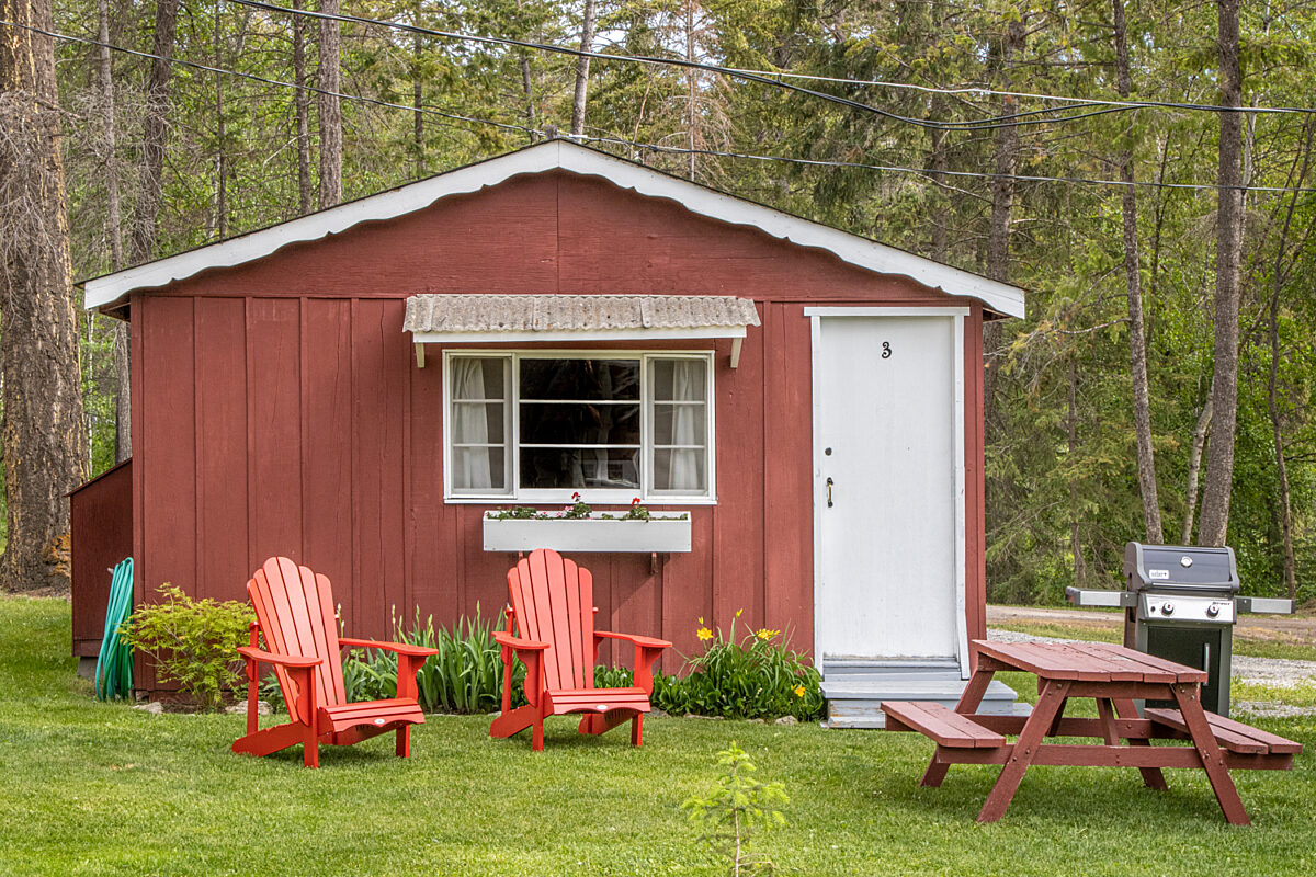 Outdoor living space with two red chairs and greenery.