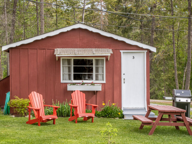Outdoor living space with two red chairs and greenery.