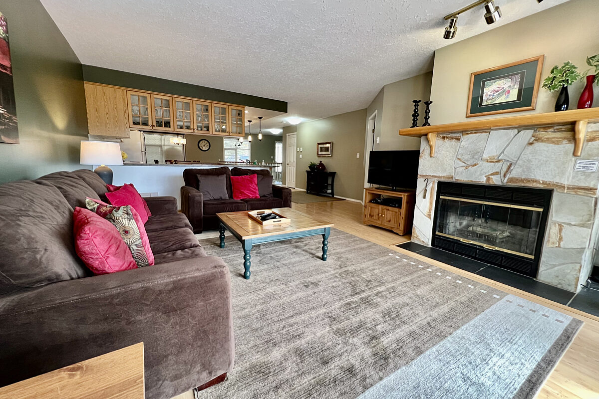 Living room with a brown velour couch, brown rug, fireplace, and coffee table.