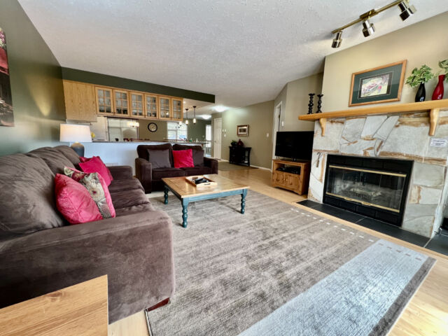 Living room with a brown velour couch, brown rug, fireplace, and coffee table.