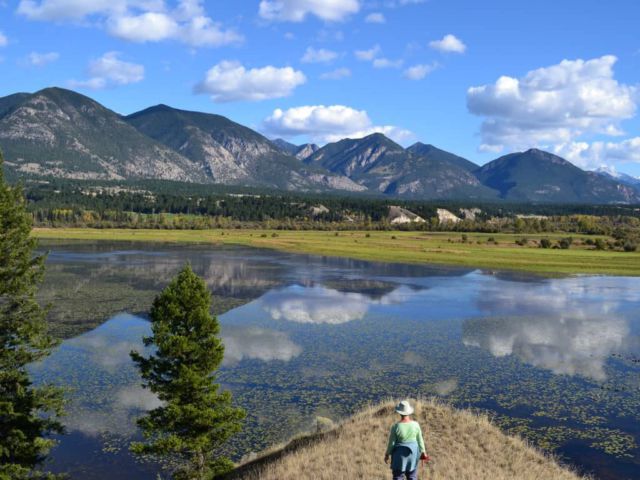 Hikers overlook a wetland and mountain area