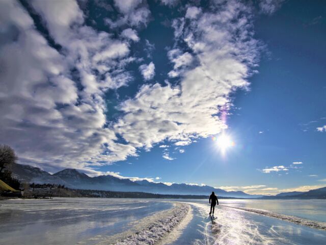 Skater enjoys skating the Lake Windermere Whiteway on a blue sky day