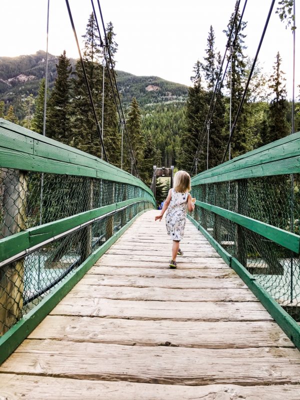 Children run across a wooden bridge atop a creek at Panorama Mountain Resort in BC