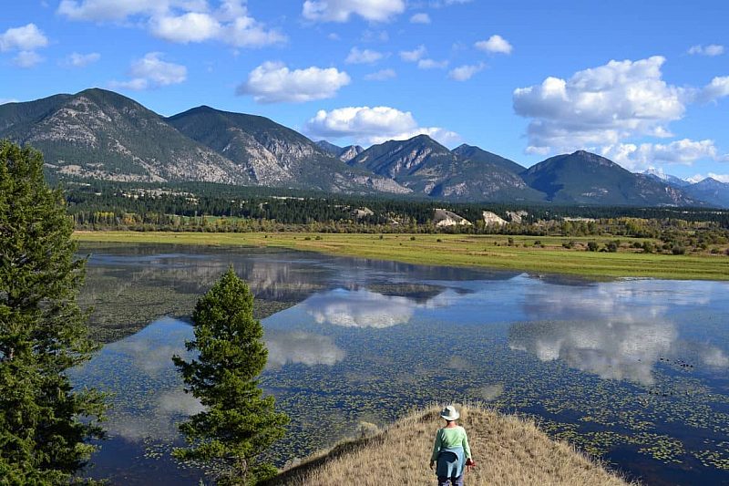 Hikers overlook a wetland and mountain area