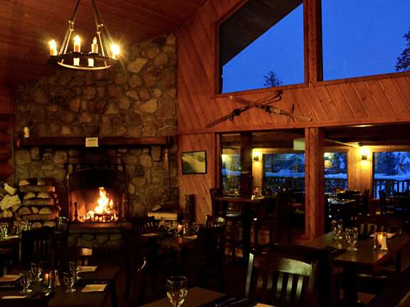 Dimly lit restaurant at nighttime with fireplace to the left.