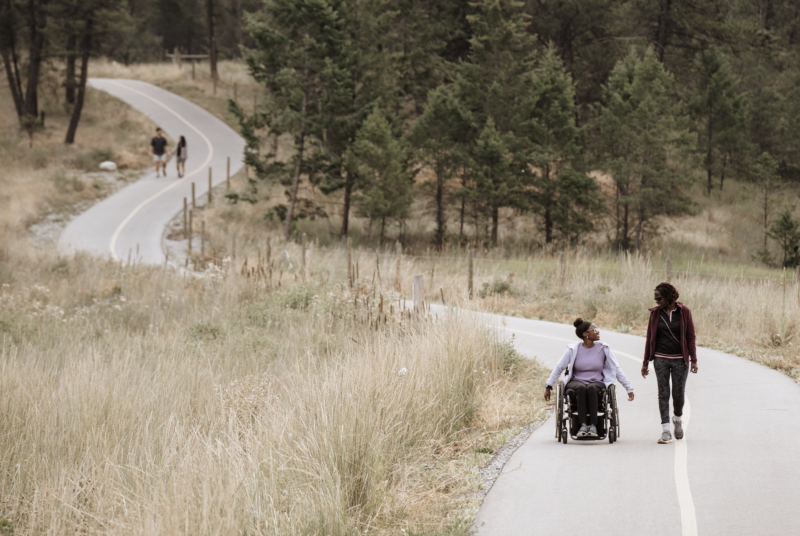 A hiker and wheelchair user on paved path