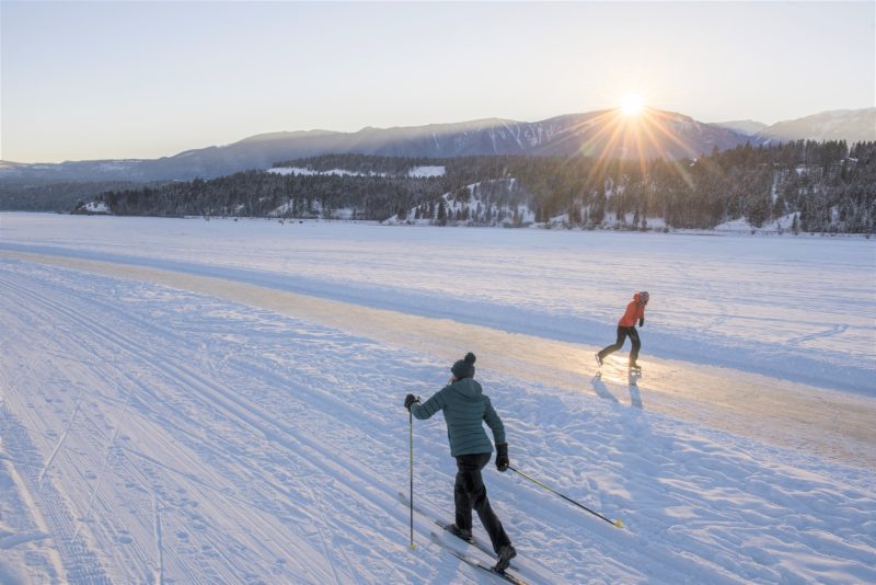 A Nordic Skiier and skater enjoy the Lake Windermere Whiteway at sunset.