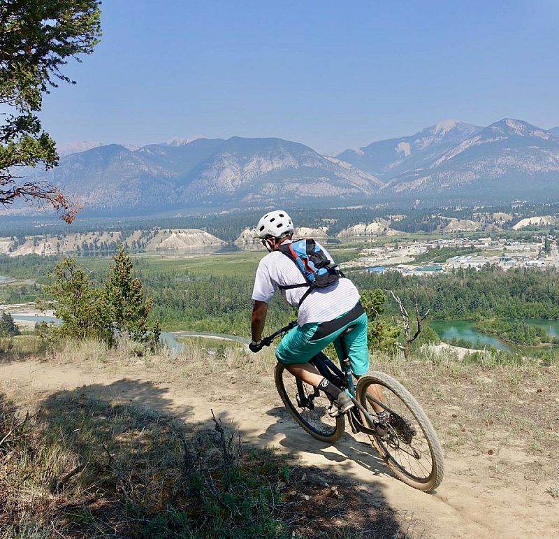 a man riding a bike down a dirt road. Blue sky.