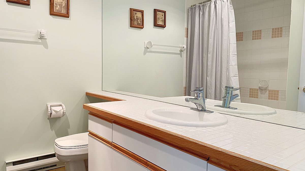 Bathroom with white walls, mirror, and cabinets