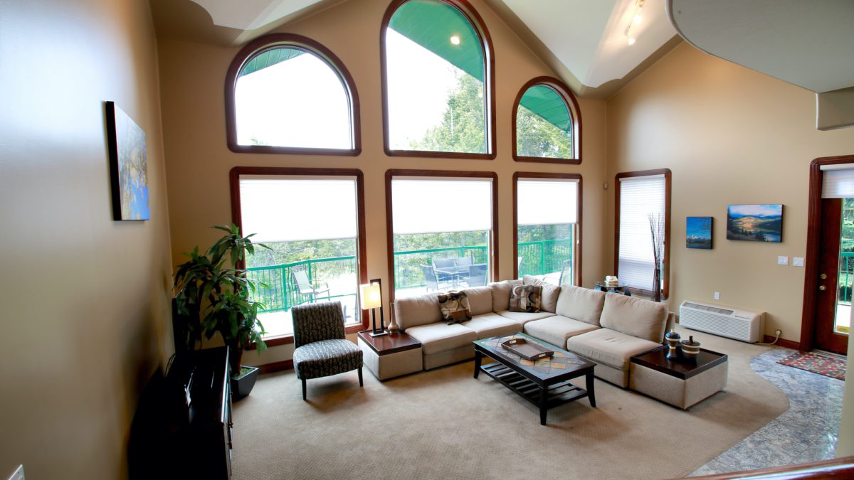 Spacious living area with couches and coffee table. Large windows to the left.