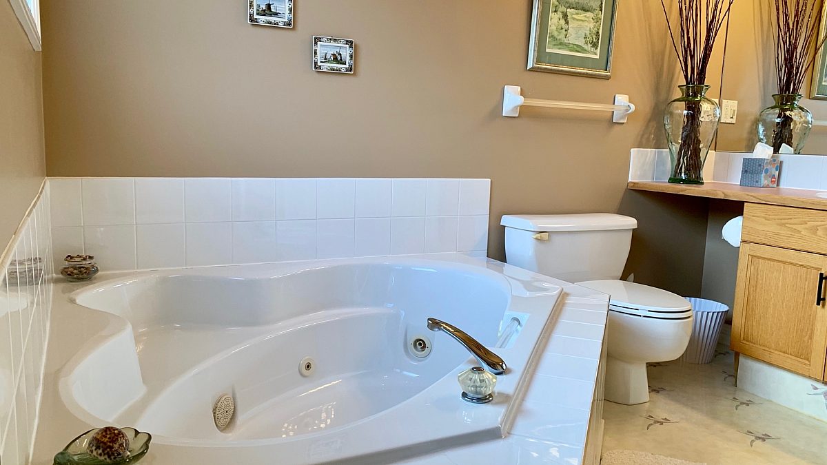 Jacuzzi tub in bathroom. Toilet and cabinets nearby.