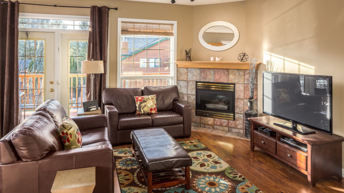 Living space with two brown leather couches, a coffee table, a fireplace, and television.