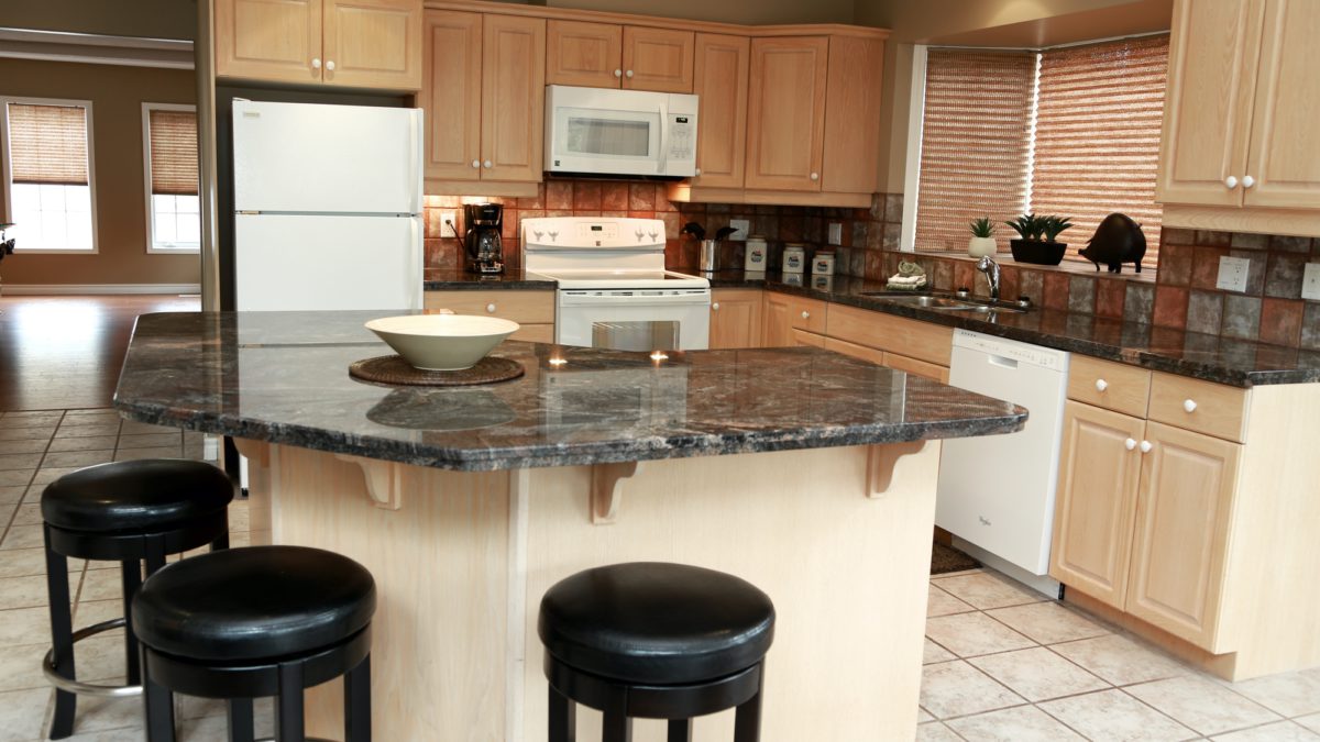 Spacious kitchen with island, barstools, appliances, and birch cupboards.
