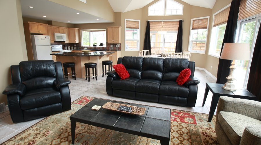 Living room with black leather couch, black leather chair, coffee table, and red pillows.
